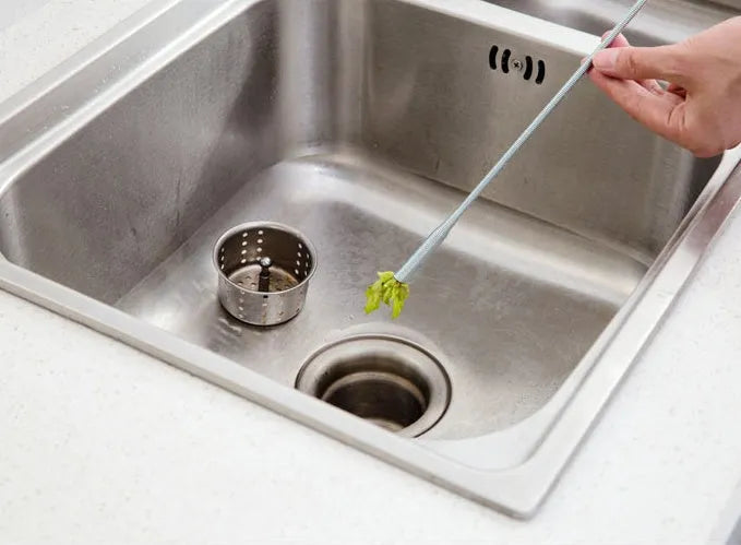 Black sewer dredge spring drain unclogging tool with PP handle next to a kitchen sink