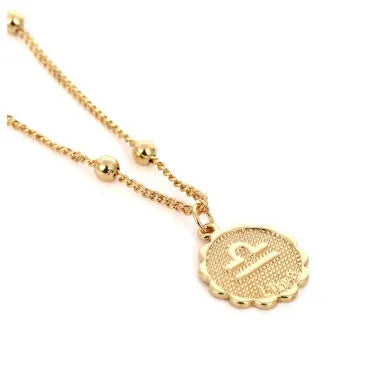 Gold plated metal zodiac constellation pendant necklace with bead chain on white background