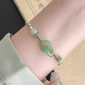 Green adjustable bracelet with jade peace buckle and copper zodiac charm.