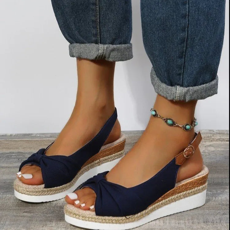 Peep toe platform sandal with one-line buckle strap, cloth upper, rubber sole, shown in black.