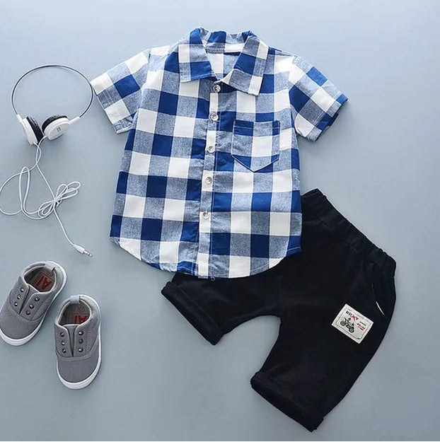 Baby boy wearing a blue crocodile print cotton t-shirt and matching blue shorts summer outfit set.