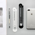 Black and white two-sided 12cm steel ruler on a wooden desk.