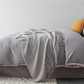 Small polyester fibre throw blanket in dark grey, shown folded, dimensions 127cm by 170cm.