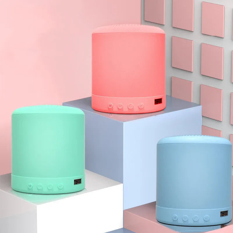 A11 compact wireless subwoofer speaker in black, pink, blue, or green colour on a desk.