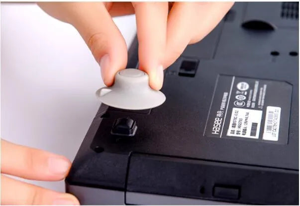 Grey plastic laptop cooling pad stand with four non-slip pads on a desk.