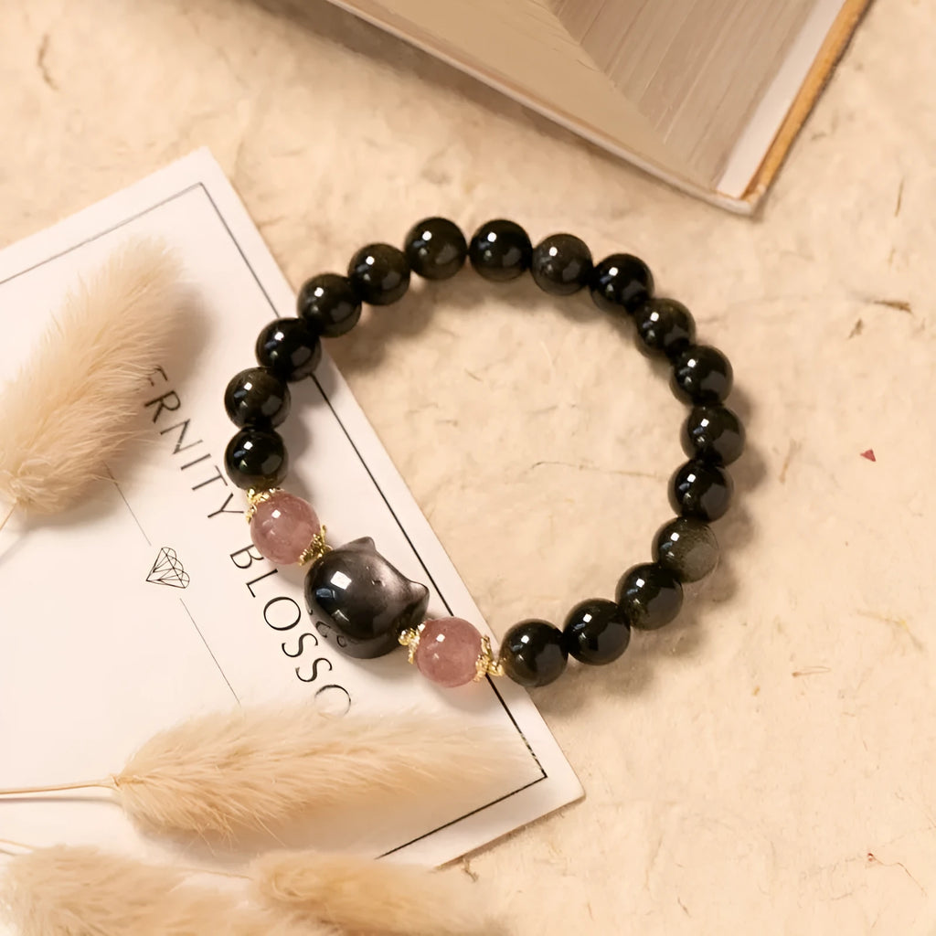 Black obsidian beaded bracelet with silver kitty cat charms on a wrist.