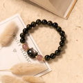 Black obsidian beaded bracelet with silver kitty cat charms on a wrist.