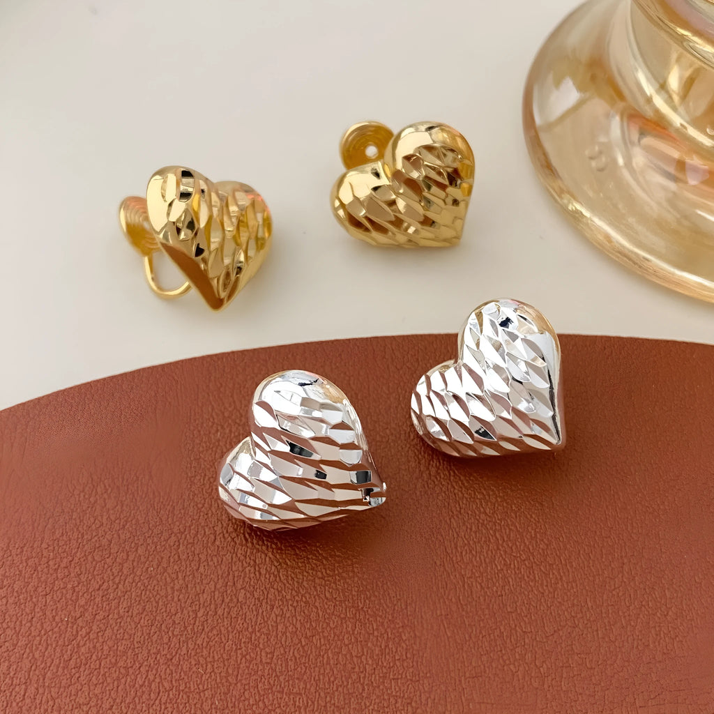 Heart-shaped copper earrings with electroplating, shown as gold or silver ear clips or studs, one pair.