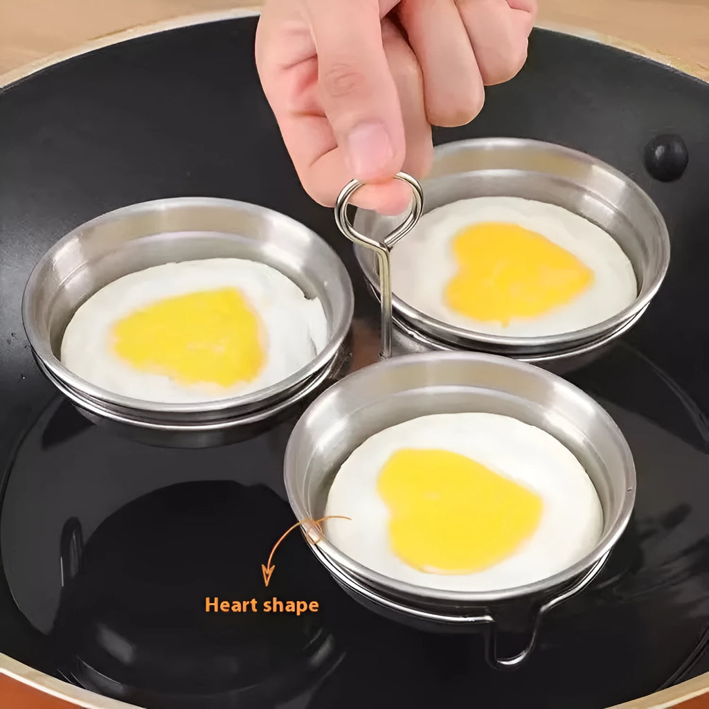 Mini stainless steel egg steamer in heart-shaped and round designs on a kitchen counter.