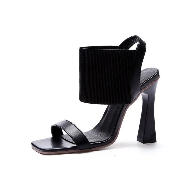 Women's black high heel sandals with a crossing elastic strap and a rubber sole.