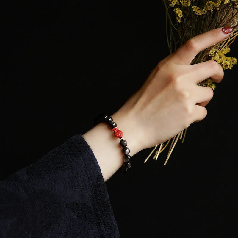 Natural black obsidian round bead bracelet with red cinnabar fungus decorative elements.