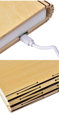 Walnut cover LED book light open at an angle showing white light pages on a surface