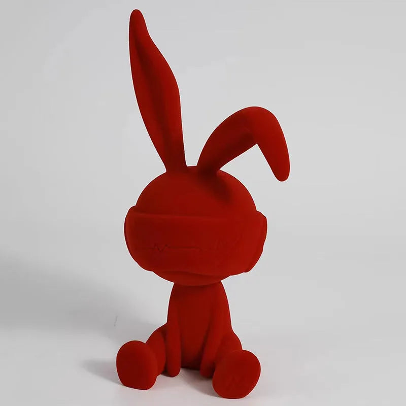 Green suede blindfold rabbit resin ornament seated on a table