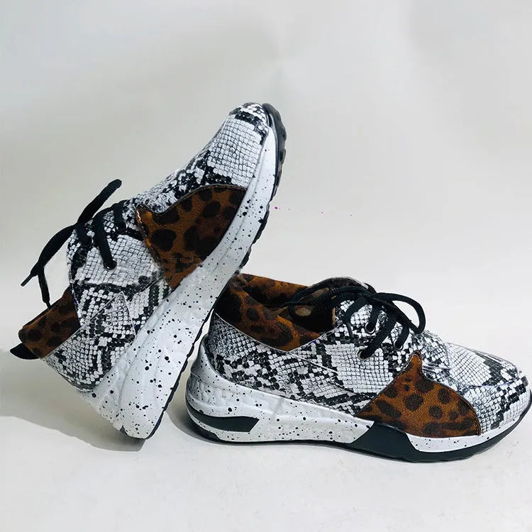 Women's black suede casual sneakers with a wedge heel on a wooden floor.