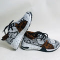 Women's black suede casual sneakers with a wedge heel on a wooden floor.
