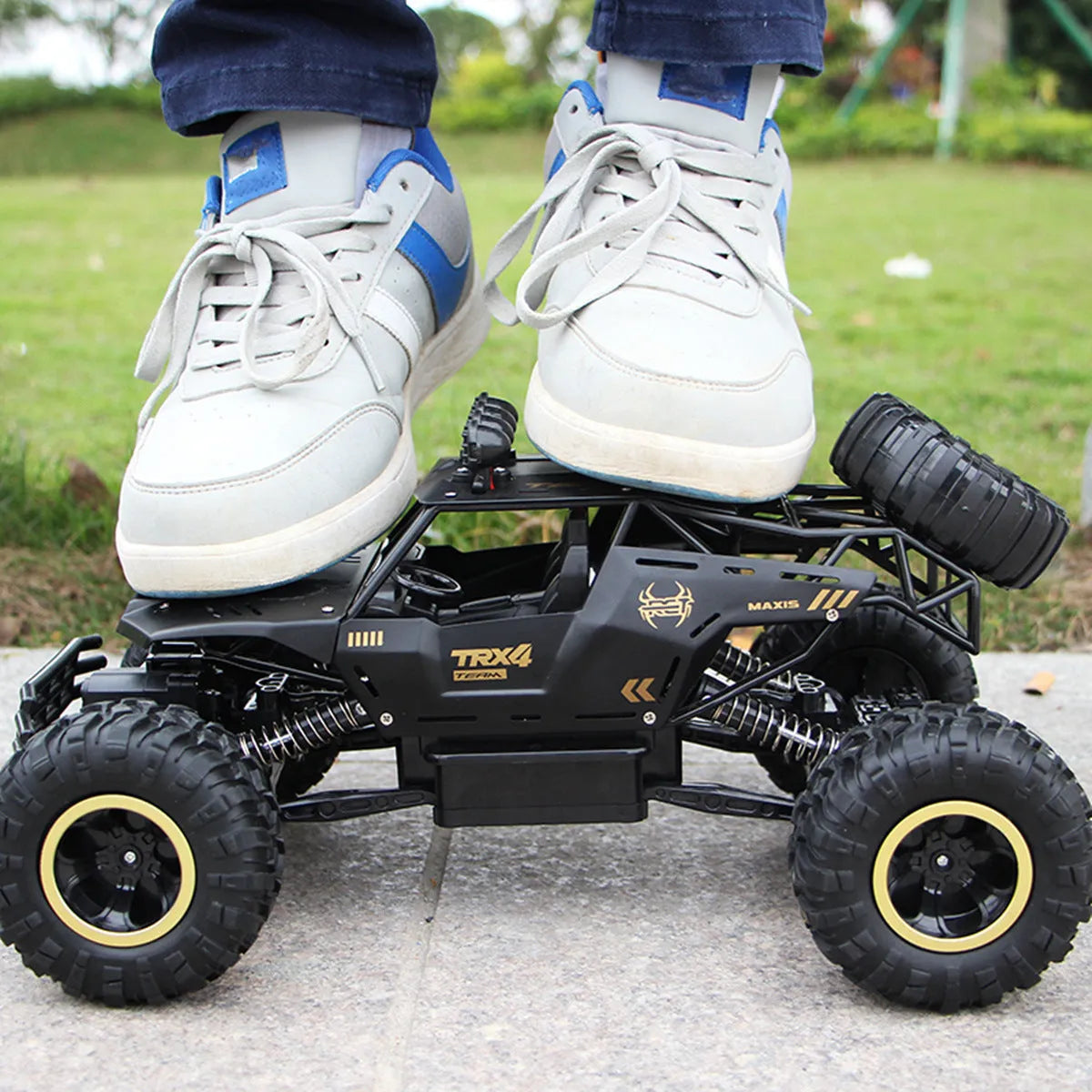 Black and silver remote control off-road car on rough terrain showing four-wheel drive and climbing capability.