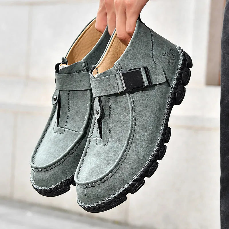 Casual black slip-on shoes with handmade stitching and a flat, low-heel sole.