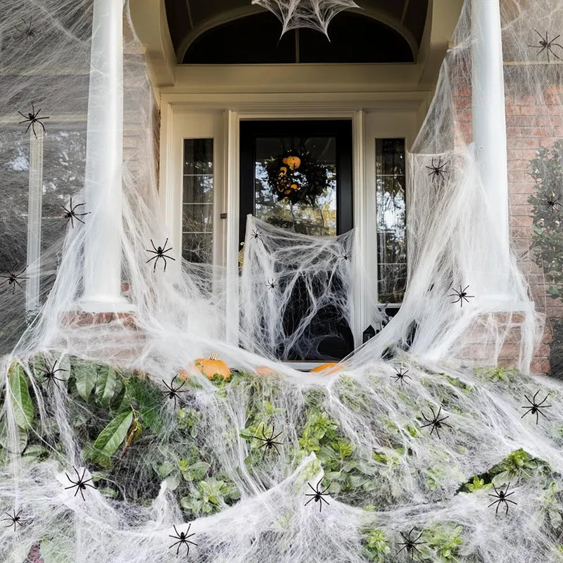 White cotton Halloween spider web decoration draped with plastic spiders for haunted house party decor.