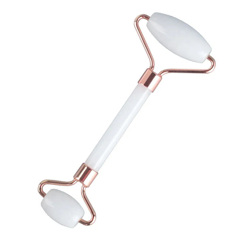 White jade facial roller with double heads and a matching gua sha scraping board on a plain surface.
