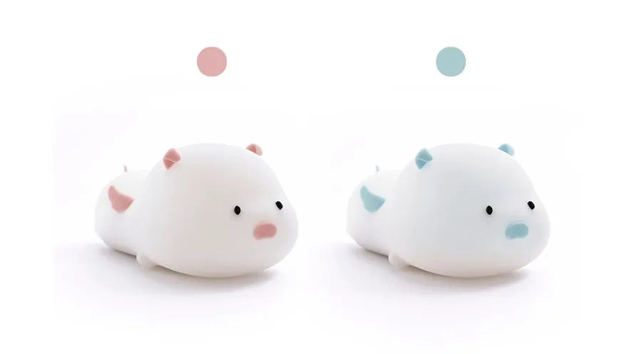 Blue silicone pig-shaped rechargeable LED night light with touch control on a wooden surface.