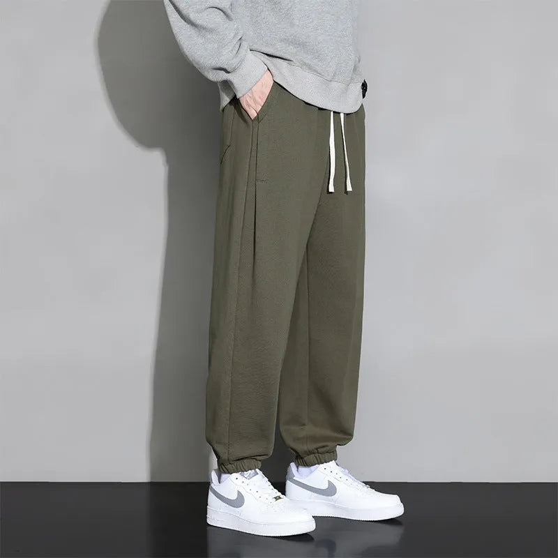 Men's loose grey cotton polyester sports trousers with elastic drawstring waist, laid flat.