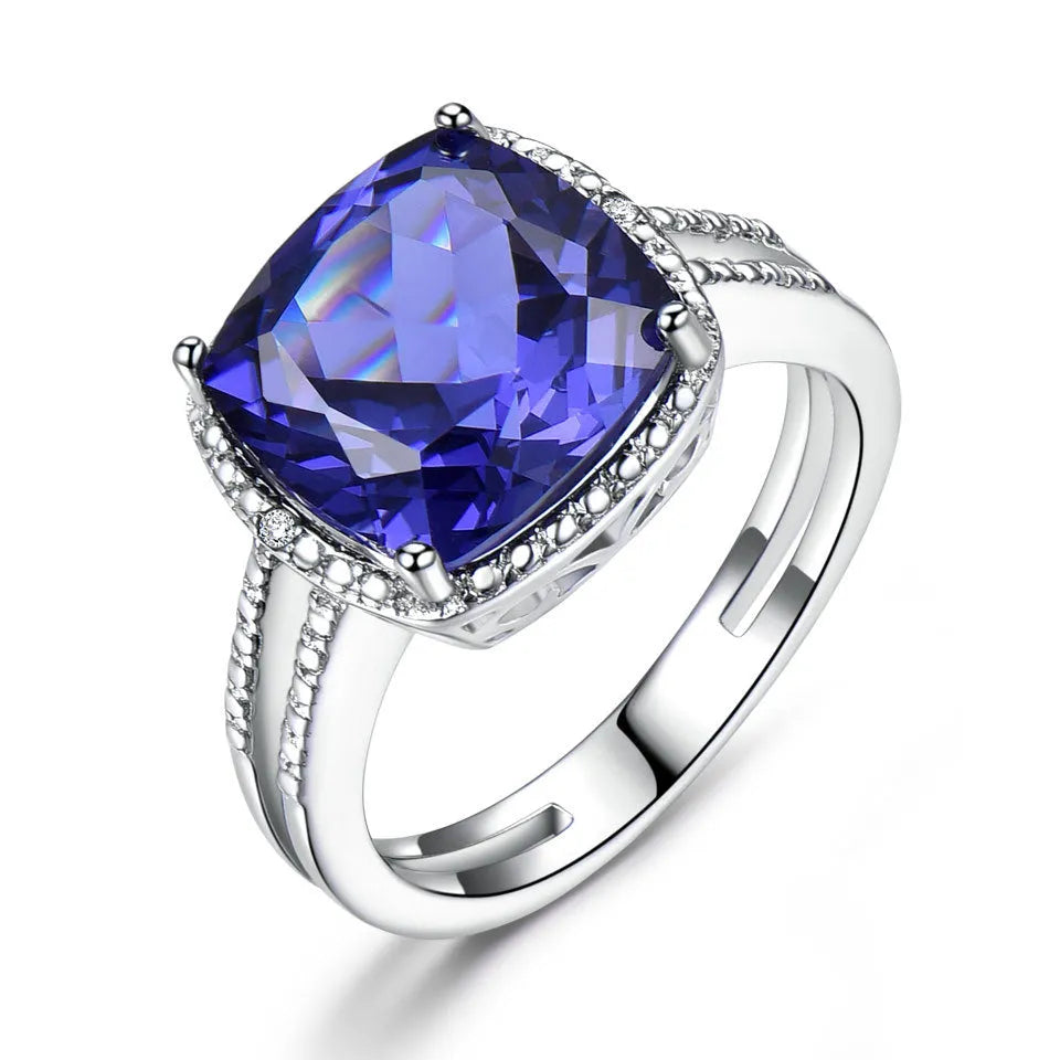Blue tanzanite stone set in a sterling silver women's ring on a grey background.