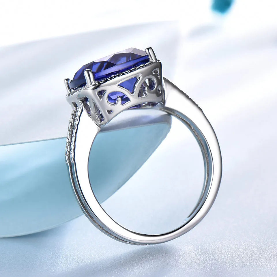 Blue tanzanite stone set in a sterling silver women's ring on a grey background.