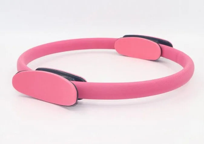Pink pilates ring with ergonomic design on white background for yoga and home workout resistance training
