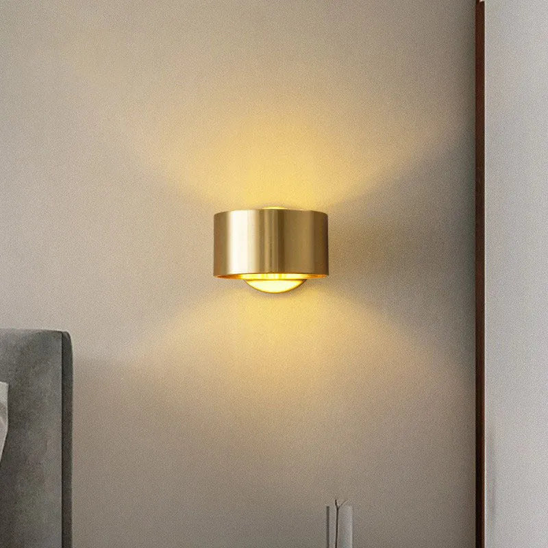 A modern simple style copper wall lamp in a gold finish, mounted on a wall.