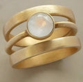 Gold-plated geometric ring with hollow design and a micro-inlaid white chalcedony stone on a titanium steel band.
