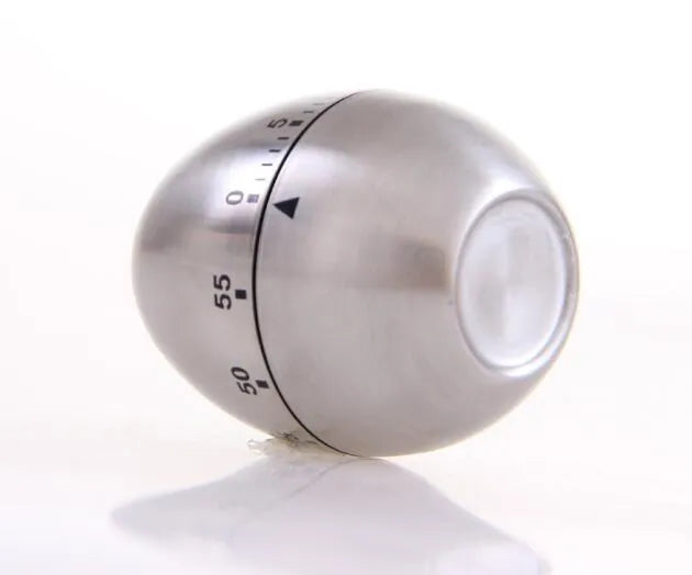Stainless steel egg-shaped mechanical kitchen timer on a kitchen worktop.