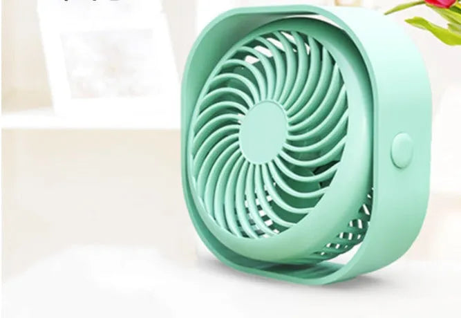A small, modern USB desk fan in blue with a rotating head on a white desk.