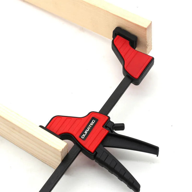 Black plastic woodworking toggle clamp with quick-release mechanism and soft rubber protective pads