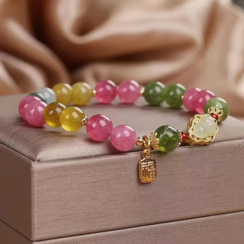 Women's bracelet with colourful tourmaline gourd blessing charm and floral clasp on a mixed material chain.