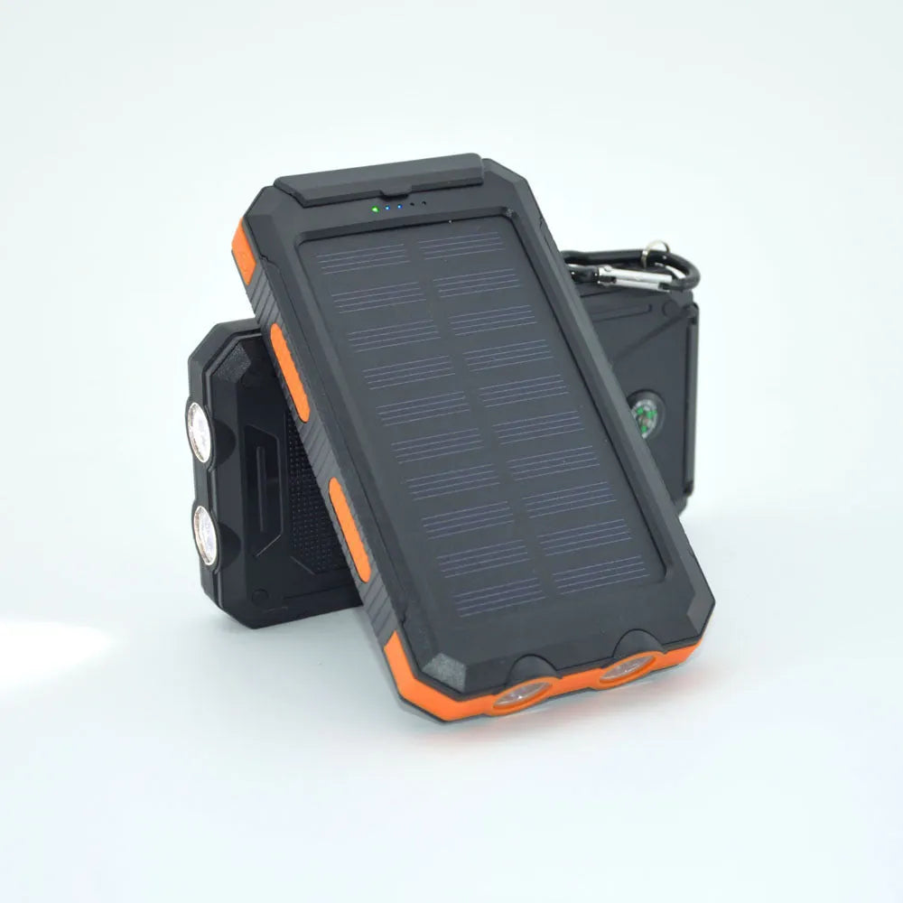 Black solar power bank showing LED flashlight, digital compass display, and solar panel on a rugged outdoor surface.