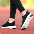 Women's running shoes in black with detailed view of fly weaving upper material and wear-resistant rubber outsole.