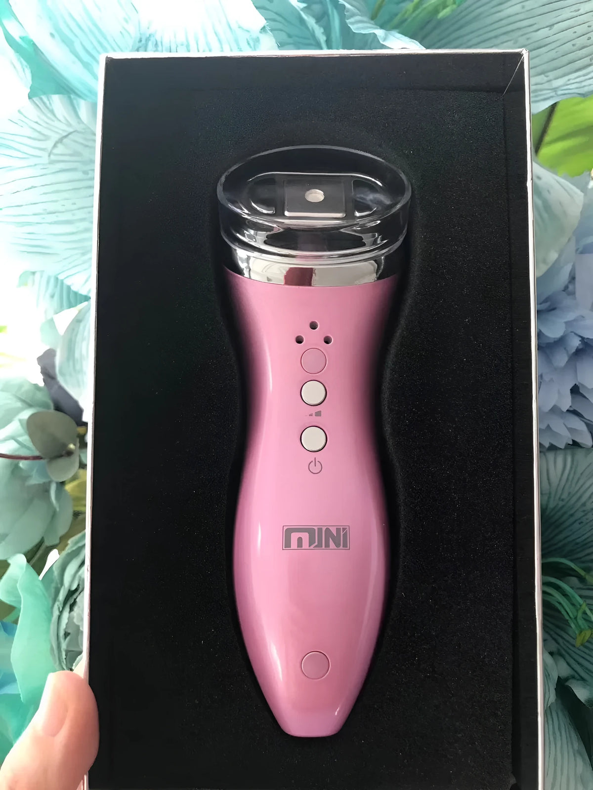 Mini ultrasonic scalpel for home facial firming in purple, with power adapter and gel on white background