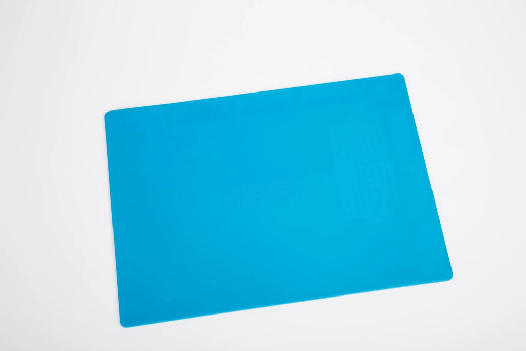 Blue silicone anti-skid watch repair mat lying flat on a workbench.