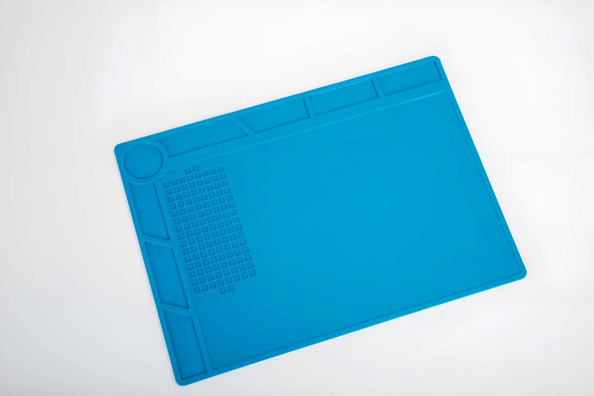 Blue silicone anti-skid watch repair mat lying flat on a workbench.