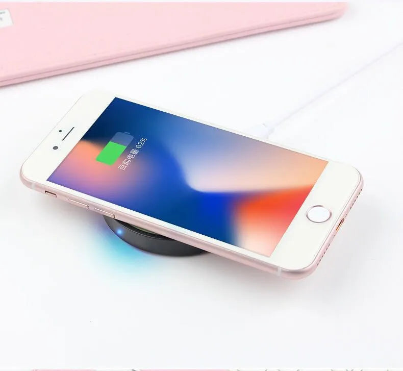 Qi wireless charging base for mobile phones in six colours on a wooden table.