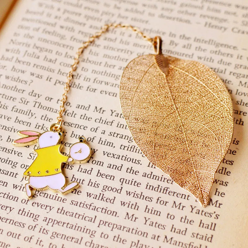 Set of three metal bookmarks featuring Alice, a rabbit, and a clock charm on a leaf base.