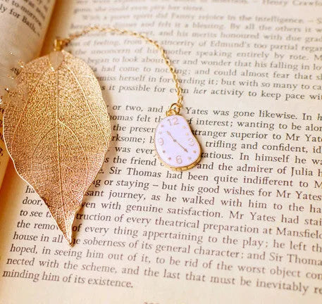 Set of three metal bookmarks featuring Alice, a rabbit, and a clock charm on a leaf base.