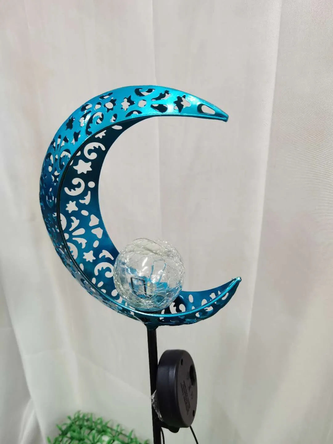 Blue moon and star design solar-powered wrought iron garden light with a glass ball.