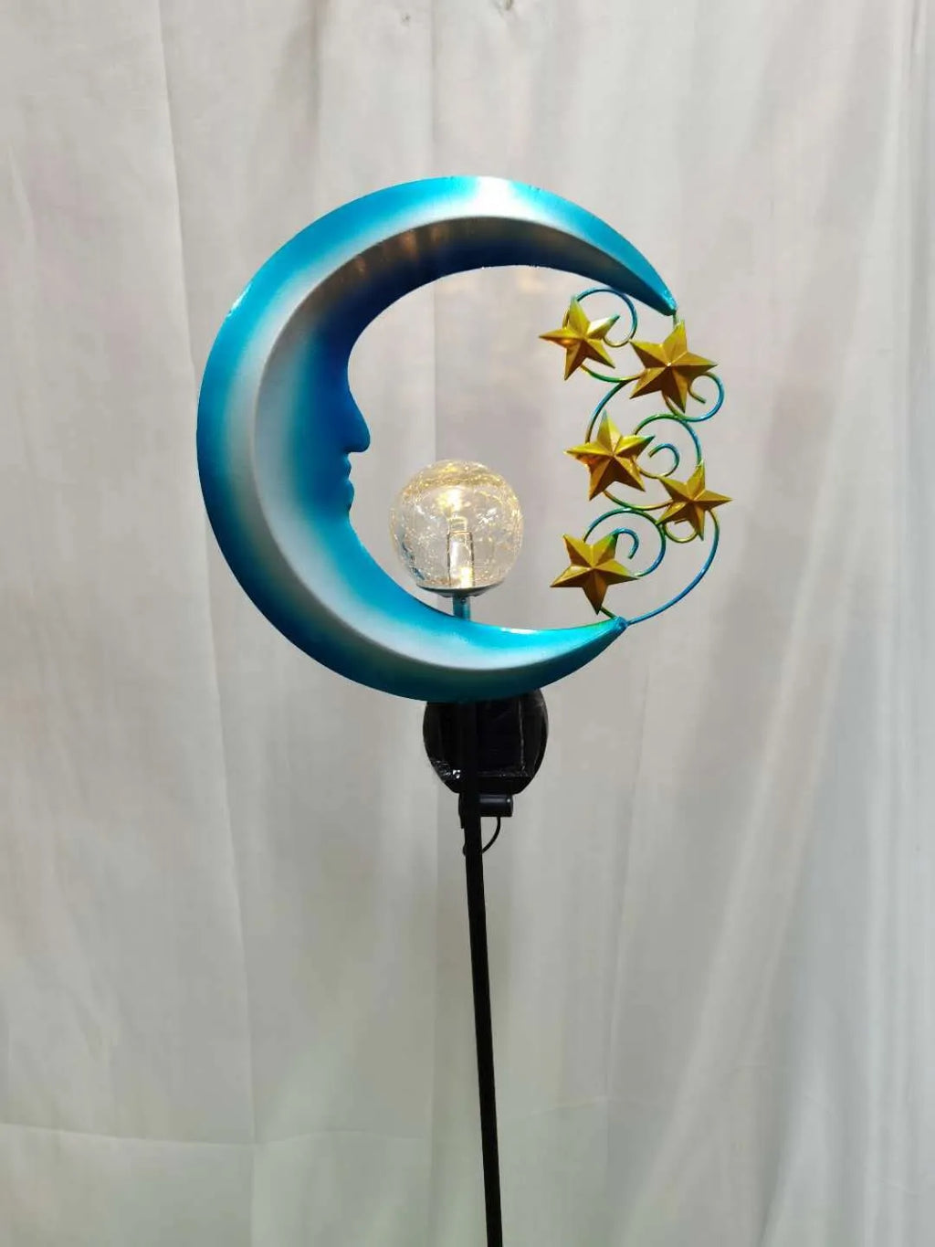 Blue moon and star design solar-powered wrought iron garden light with a glass ball.