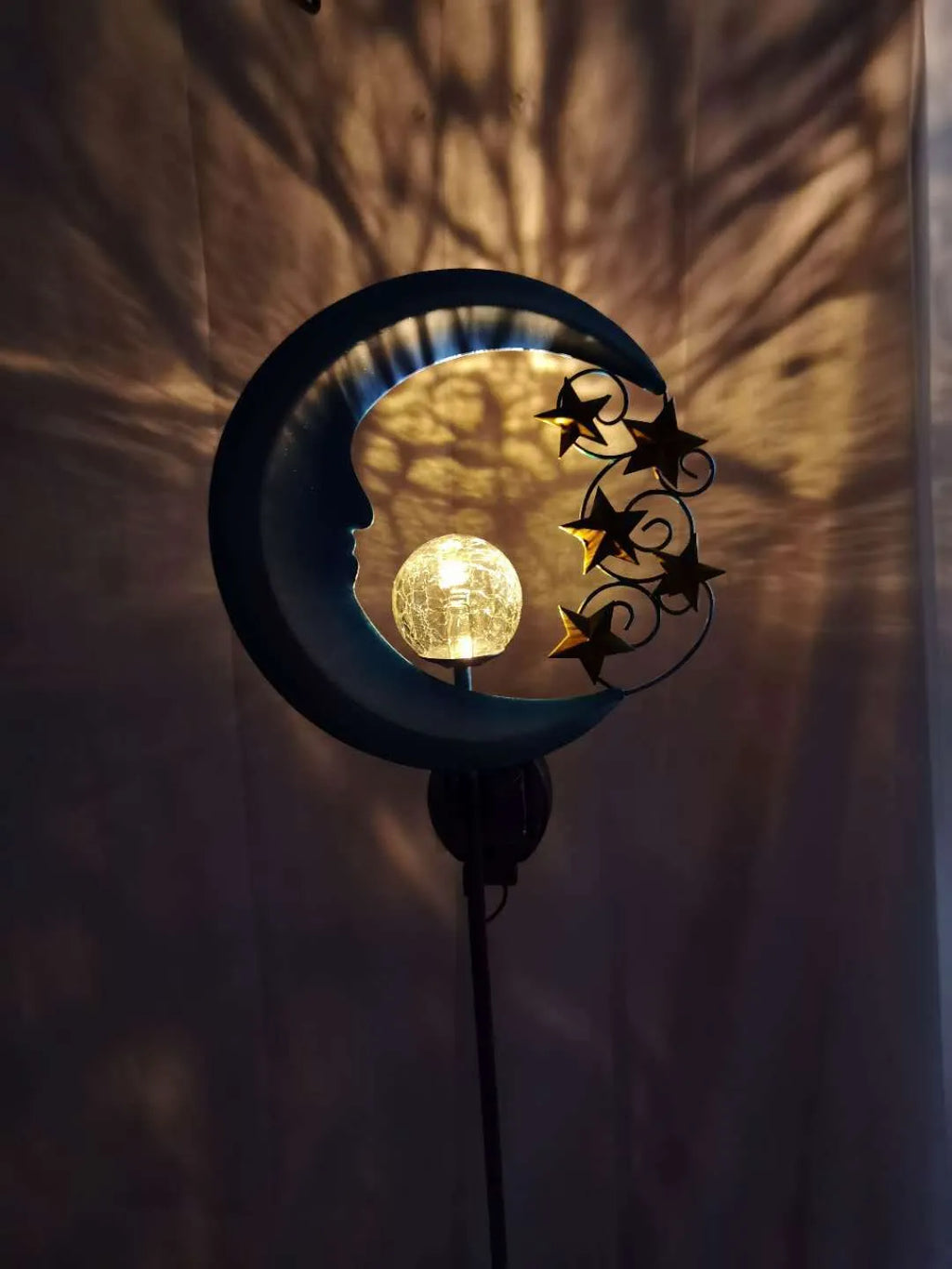Blue moon and star design solar-powered wrought iron garden light with a glass ball.
