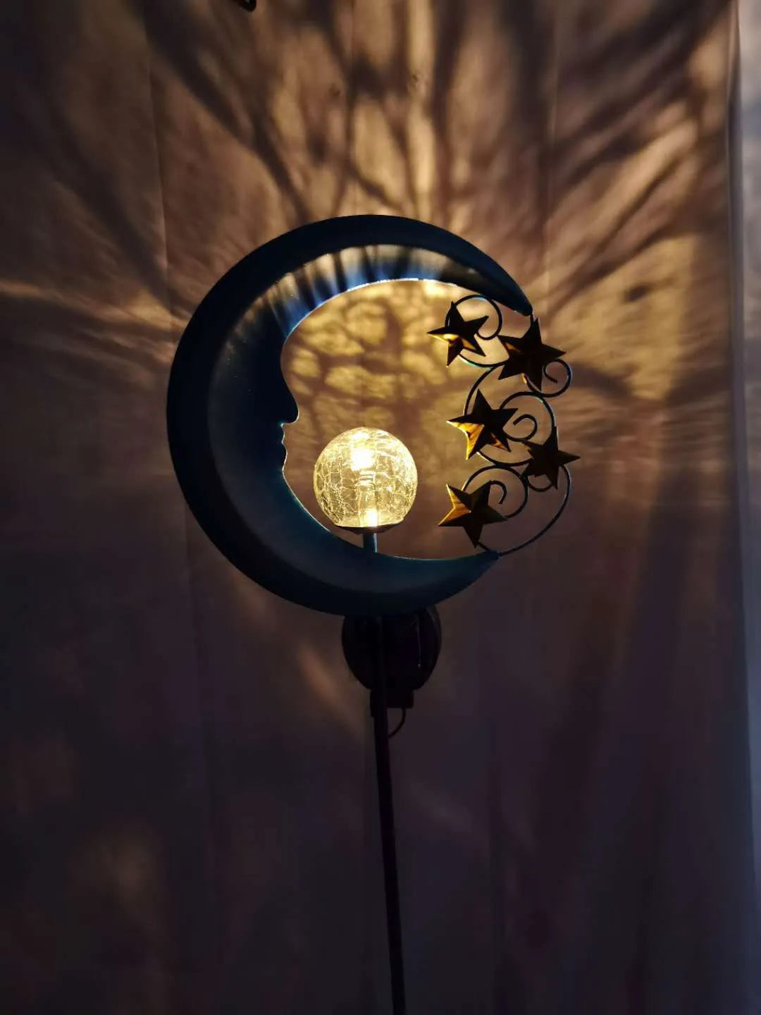 Blue moon and star design solar-powered wrought iron garden light with a glass ball.