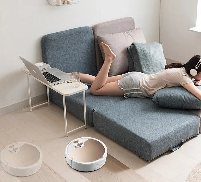 Golden and silver intelligent robot vacuum cleaner with remote control on wooden floor