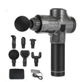 Black electric muscle massage gun with 7 different attachment heads on a table.