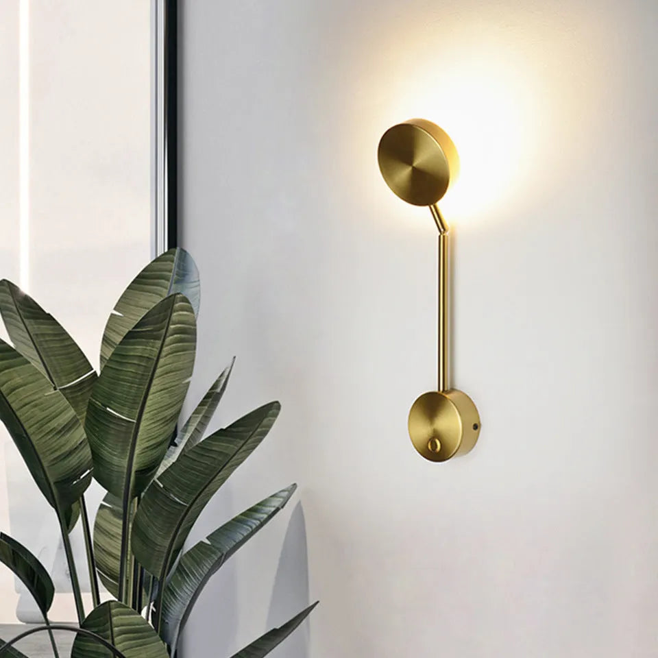 Gold LED wall lamp with rotary switch and acrylic shade on a wall