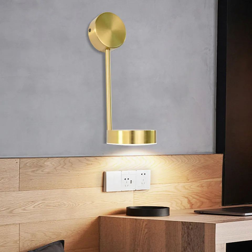 Gold LED wall lamp with rotary switch and acrylic shade on a wall
